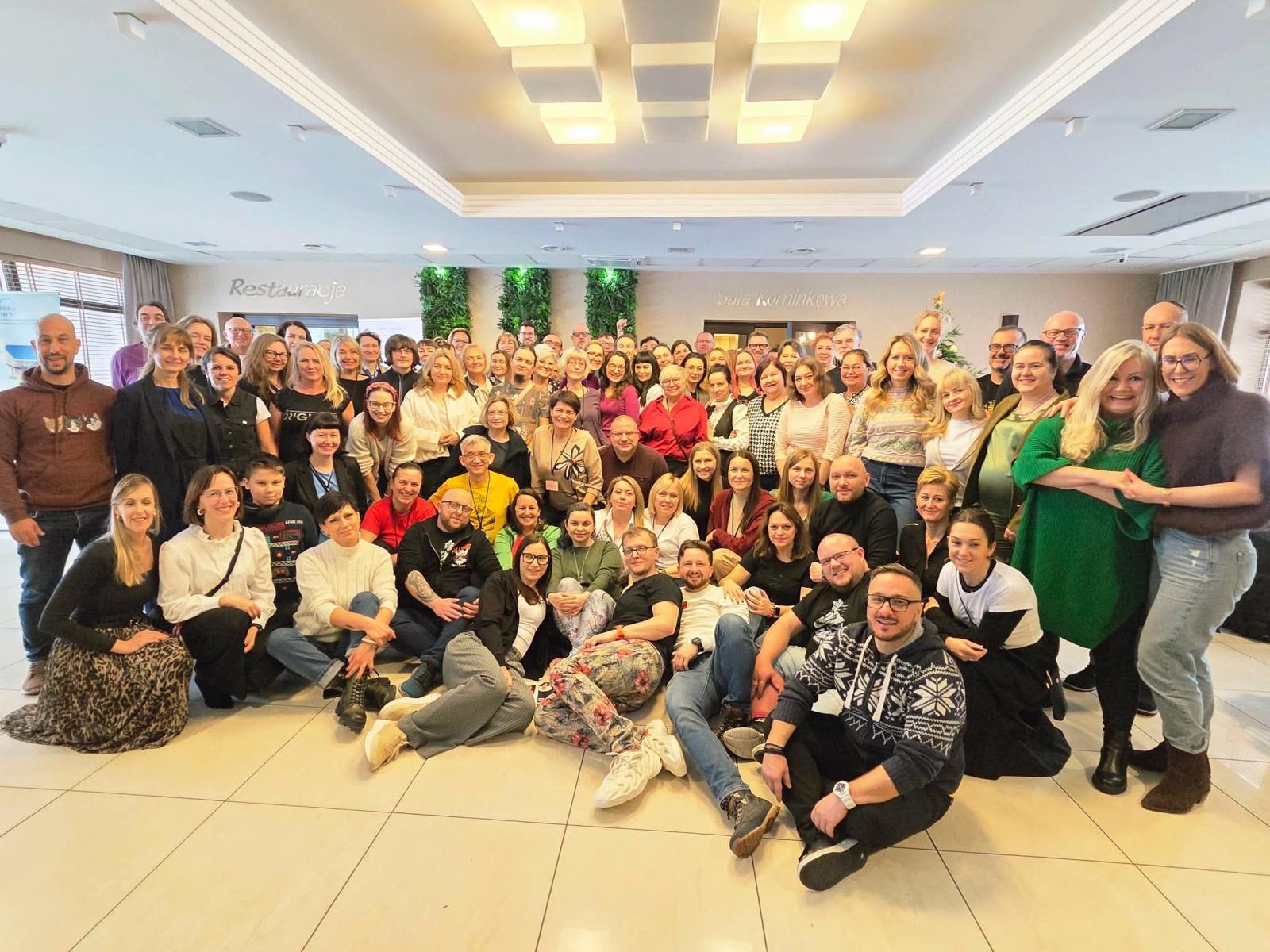 Grupa trenerów biznesu na wspólnym zdjęciu, uśmiechnięci radośni ludzie w sali szkoleniowej